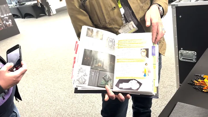 A page of the working reference book, photographs and printed notes marked up in highlighter.