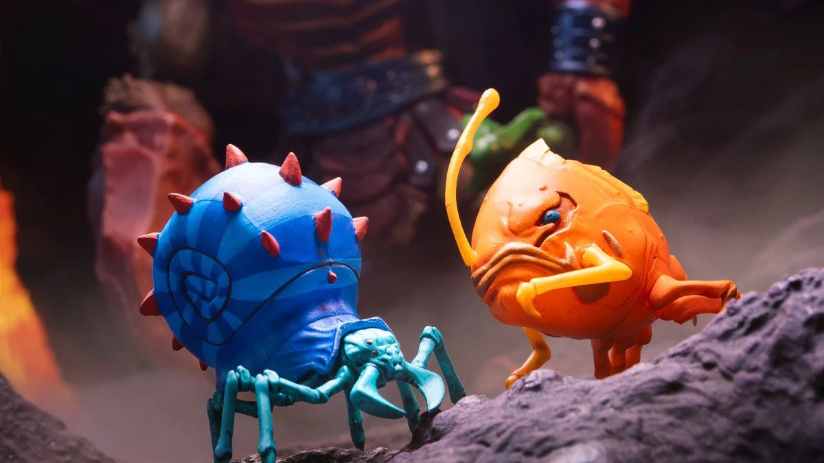 The two critter accessories packed with the standard Clawful figure: a blue spiked shell on turquoise crab legs, and an orange angler fish with a yellow lure, both on the rock base with Clawful out of focus behind them.