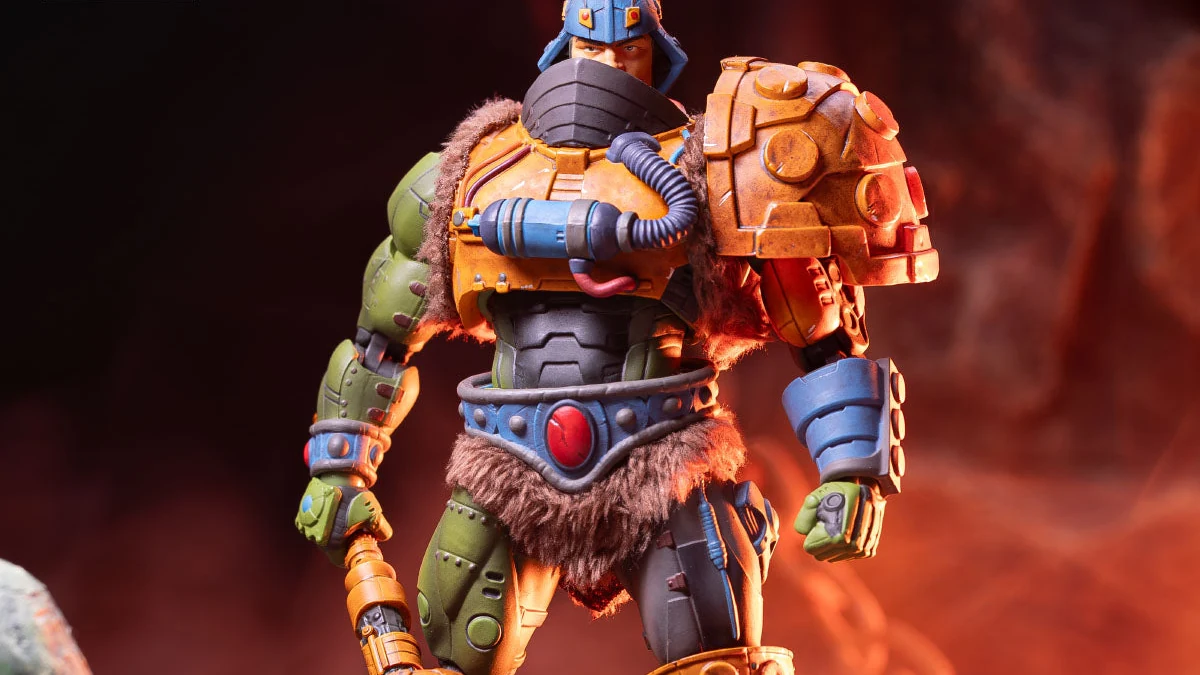 The standard MOTU200X Man-At-Arms 1/12 figure, helmet and face mask on, showing the faux fur kilt and shoulder trim, the orange shoulder cannon, the blue and grey blaster arm and the red-gemmed belt.