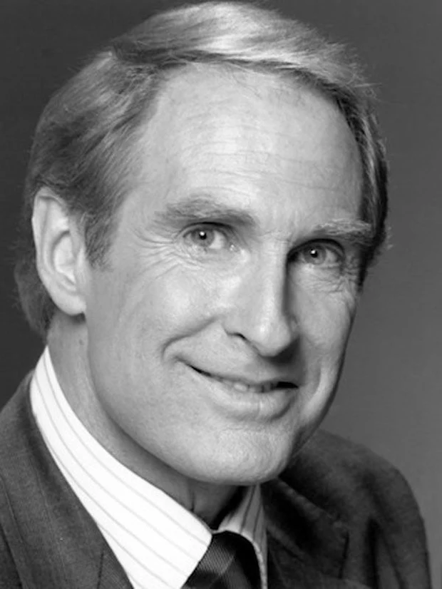 Publicity portrait of Jon Cypher, smiling, in a suit and tie.