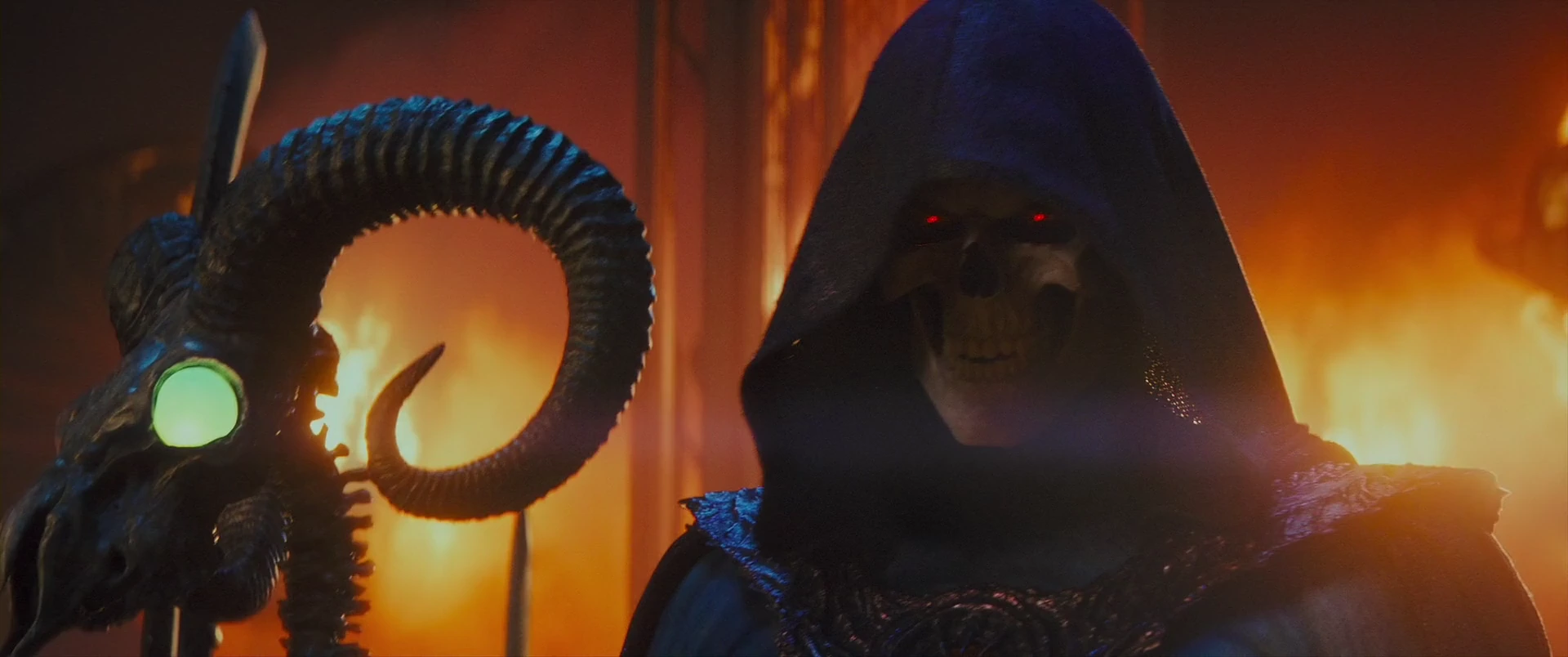 Skeletor, the skull-faced sorcerer Keldor, advances through the flames with his ram-skull staff.