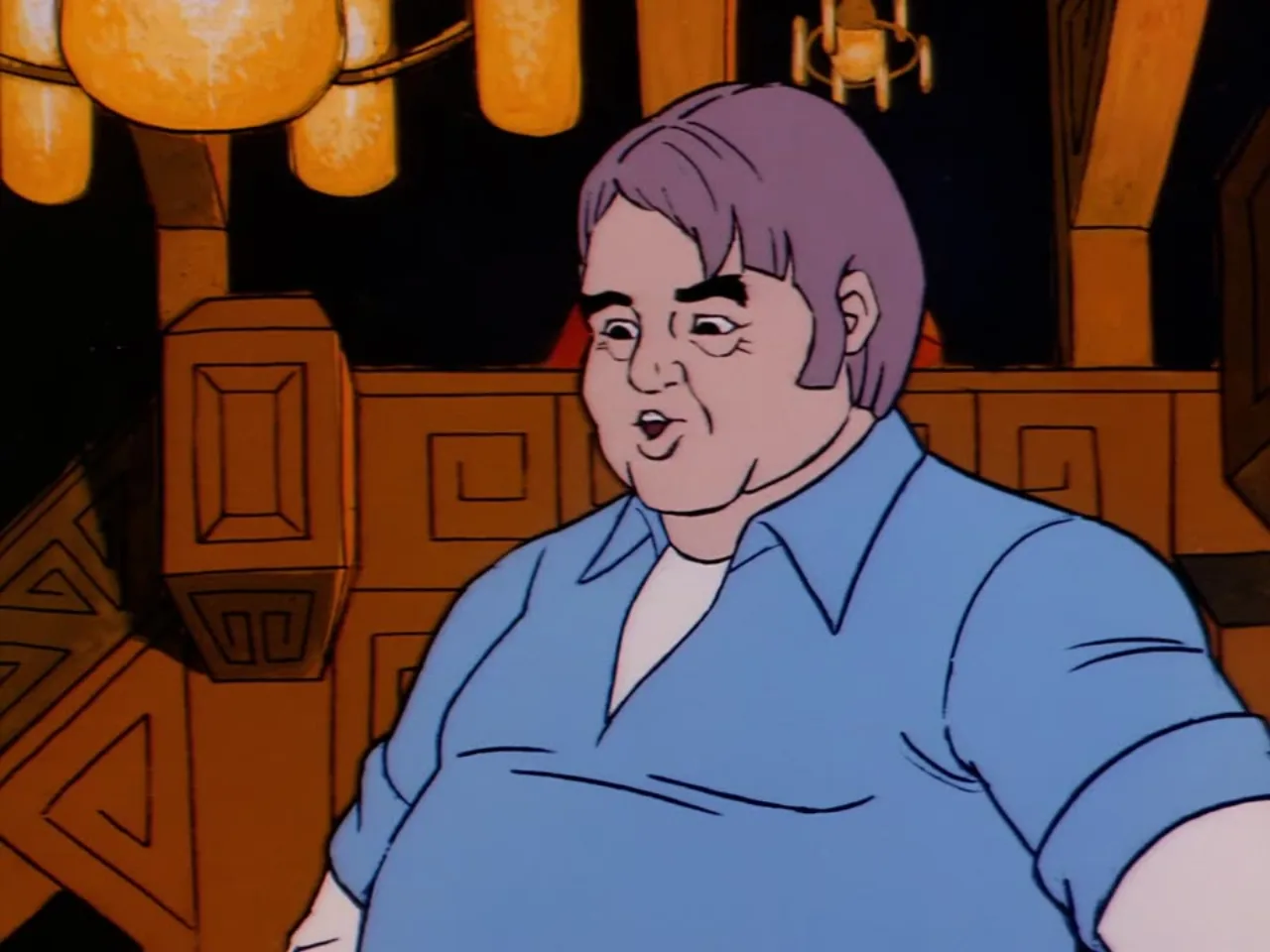 A heavyset man with lavender hair speaks animatedly inside a warmly lit wooden hall.