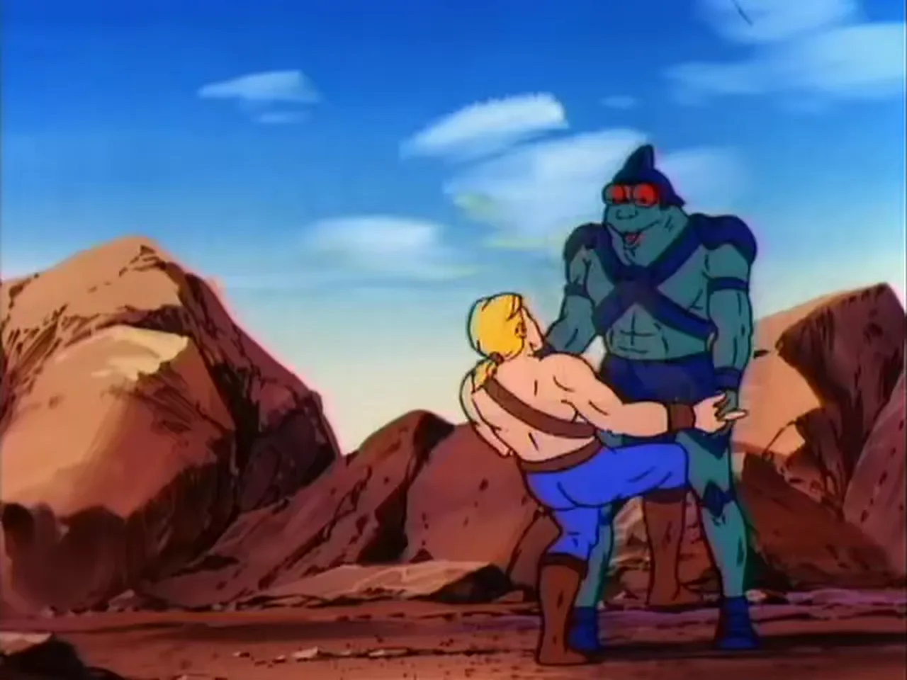 He-Man and Dreadator grip each other chest to chest between red rock formations.