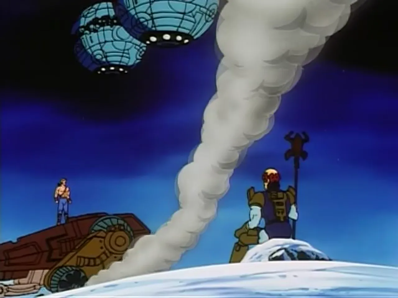 He-Man stands on a snowbound wreck as a figure with a skull-topped staff stands by a smoke plume.