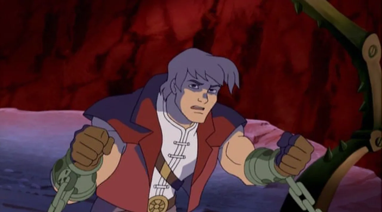 Prince Adam is shackled and strains at the chains in a red-lit cell