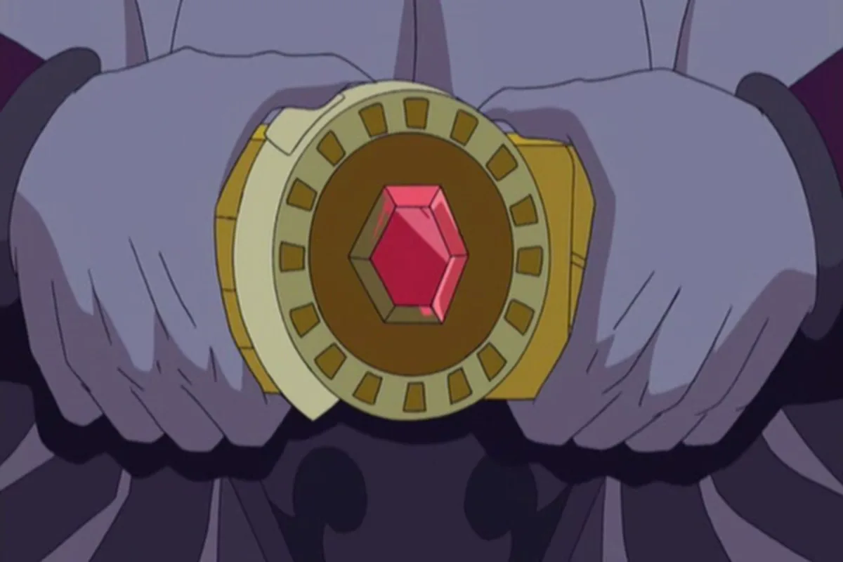 Skeletor holds a jeweled gold device with a red gem in both hands